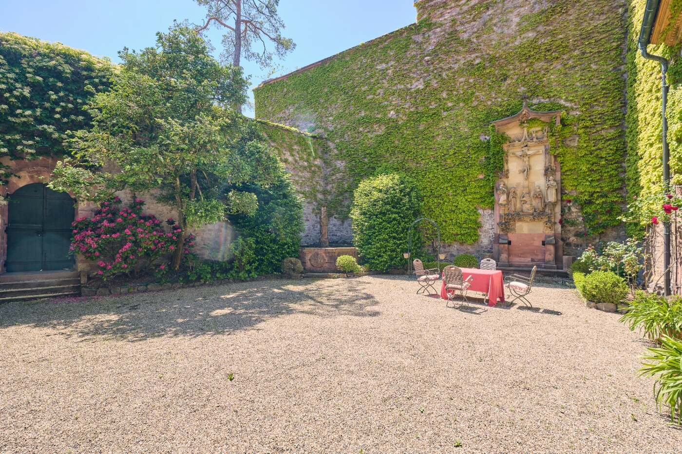 Innenhof mit historischem Kruzifix und blühenden Rosen